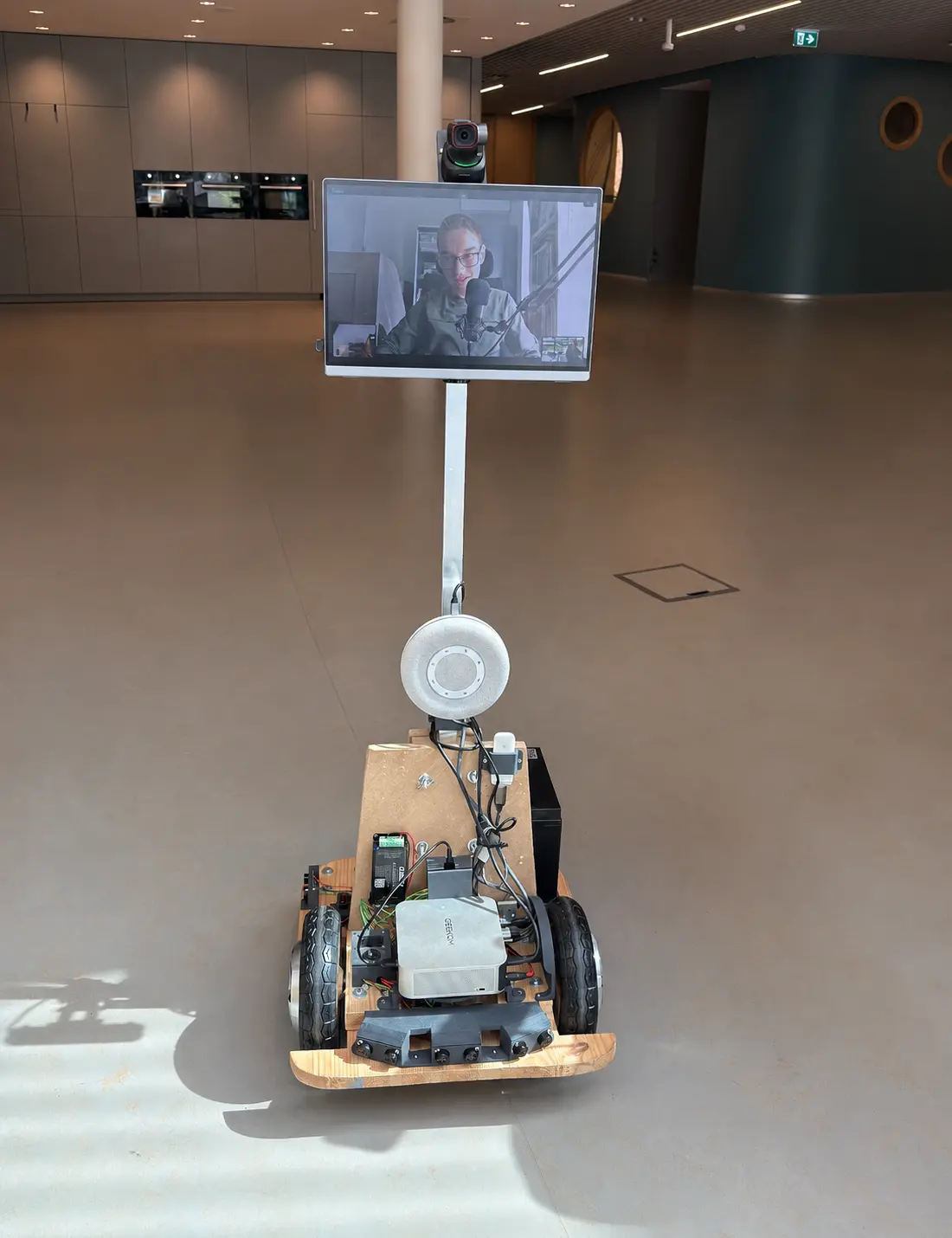 IP-Car robot in a school hallway, with Thomas visible on the screen joining class remotely from home